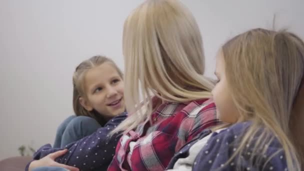 Närbild sida syn på blond kaukasiska läsa bok och förklara något för äldre flicka. Leende ung mor som utbildar barn hemma. Underrättelse, enhet, omsorg. — Stockvideo