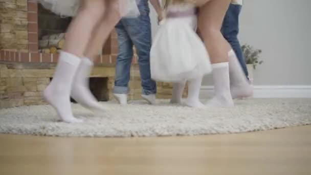 Masculino y hembra piernas caucásicas bailando en alfombra suave frente a la chimenea. Gente de diferentes edades de fiesta en el interior. Gran familia feliz divirtiéndose . — Vídeo de stock