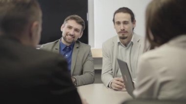 Takım elbiseli beyaz ofis çalışanlarının omzundan ateş ederek meslektaşlarını ya da iş ortaklarını dinliyorlar. Ekip toplantıda yeni projeyi tartışıyor. Takım çalışması, iletişim, anlaşma.