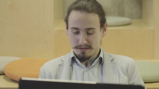 Retrato de close-up do jovem caucasiano com bigodes e barba olhando para laptop. Empresário positivo a trabalhar online. Sucesso, excesso de trabalho, negócios, profissional . — Vídeo de Stock