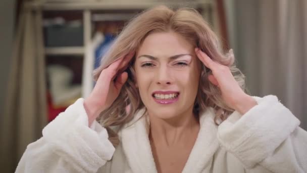 Close-up of pretty Caucasian woman with severe headache. Beautiful girl holding temples with hands having hurt facial expression. Healthcare, health, migraine. — Stock Video