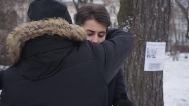 Onherkenbare jongeman die wanhopige blanke vrouw omhelst met advertenties van vermiste personen. Mooi brunette meisje met bruine ogen op zoek naar haar verloren vader. Depressie, wanhoop, verlies. — Stockvideo