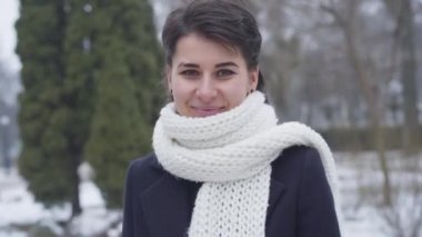 Kamera, beyaz atkısı olan beyaz atlı güzel beyaz bir kızın yüzüne biraz zum yapıyor. Kameraya bakıp gülümseyen güzel bir genç kadının portresi..
