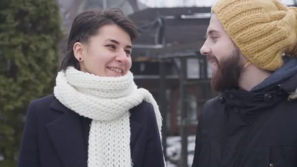 Primer plano de una joven pareja caucásica paseando por la calle de invierno. Feliz hombre y mujer hablando y sonriendo. Unidad, ocio, estilo de vida . — Vídeos de Stock
