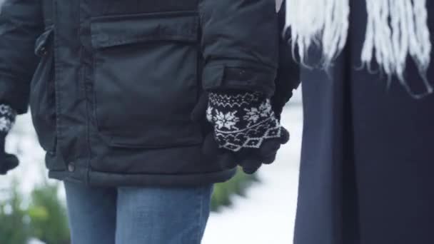 Close-up van mannelijke en vrouwelijke handen in winterhandschoenen die elkaar vasthouden. Man en vrouw wandelen buiten. Vrije tijd, levensstijl. — Stockvideo