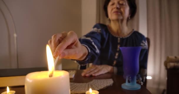 Close-up van de vrouwelijke blanke hand die de kaars op de voorgrond steekt. Oude waarzegster aan tafel aan het begin van het ritueel. Bioscoop 4k Prores Hq. — Stockvideo