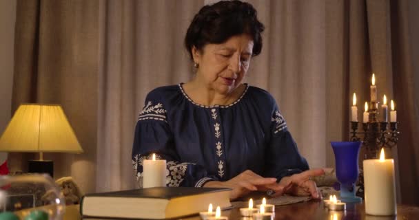 一个严肃的白人老妇人躺在桌旁和卡片交谈。 神秘的黑发女士准备在卡片上讲述未来。 占卜，占卜，仪式。 电影4k Prores Hq. — 图库视频影像