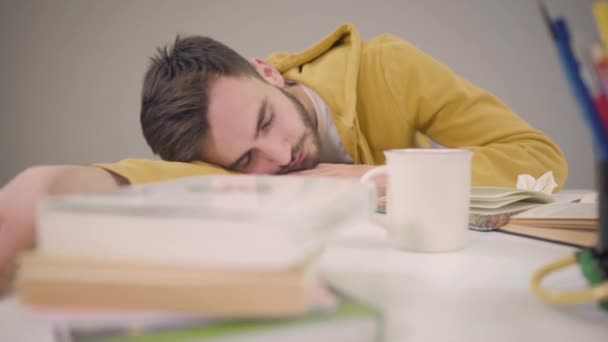 Camera beweegt van links naar rechts, twee jonge studenten slapen aan tafel. Blanke man met baard en mooie Afro-Amerikaanse vrouw moe door hard studeren. Onderwijs, overwerk. — Stockvideo