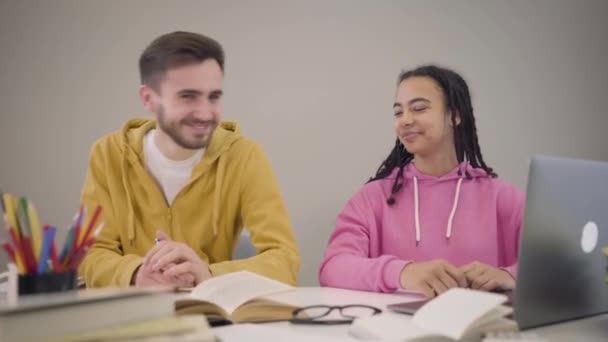 Camera approaching to young smiling students looking at camera and hugging. Portrait of happy Caucasian boy and African American girl. Lifestyle, happiness. — Stok video