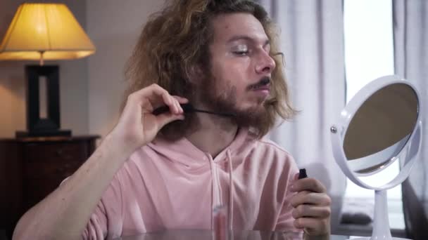 Portret van volwassen blanke niet-binaire transgender met make-up die mascara op baard aanbrengt. Zelfbeeld, genderidentiteit, minderheidsproblemen. — Stockvideo