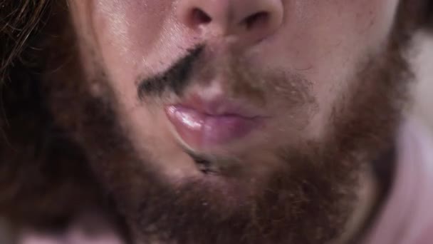 Extreme close-up of lower part of males face moving lips and smiling. One side of face with applied makeup, other one is clear. Demonstration of two sides of binary gender people. — ストック動画