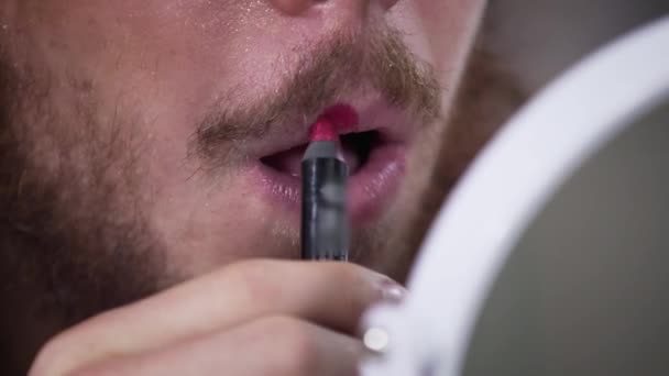 Primer plano del hombre caucásico con barba y bigotes aplicando lápiz labial rojo en un lado del labio superior. Ilustración de la persona intersexual que expresa ambos lados de la individualidad. Sexo binario, transgénero . — Vídeos de Stock