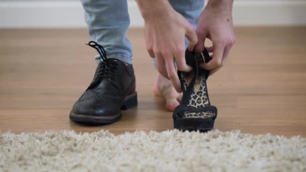 Κοντινό πλάνο του Καυκάσιου ενήλικου άντρα που φοράει ανδρική μπότα και γυναικεία ψηλοτάκουνα παπούτσια. Εικονογράφηση του δυαδικού φύλου, intersex άτομα. — Αρχείο Βίντεο
