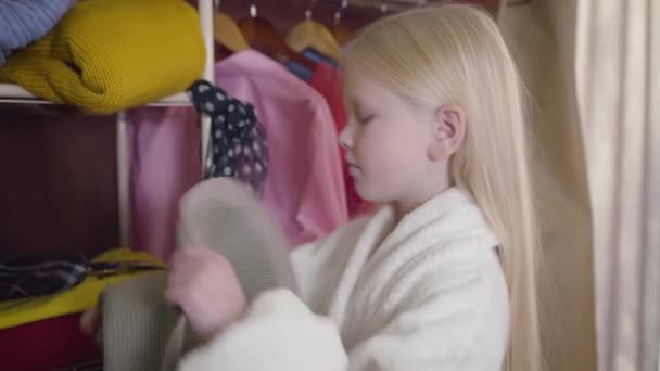 Gros plan vue de côté de fille caucasienne portant chapeau et lunettes. Portrait d'un petit mignon essayant des vêtements à l'intérieur. Élégance, mode, joie . — Video