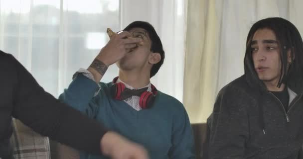 Närbild på tre unga vita män som äter pizza och pratar. Glada universitetsstudenter vilar inomhus på helgerna. Cinema 4k Prores Hq. — Stockvideo