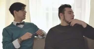 İki Kafkasyalı üniversite öğrencisi kanepede oturup konuşuyorlar. Erkek arkadaşlar ev ödevlerini tartışıyor. Zeka, eğitim konsepti. Sinema 4k Prores Merkezi.