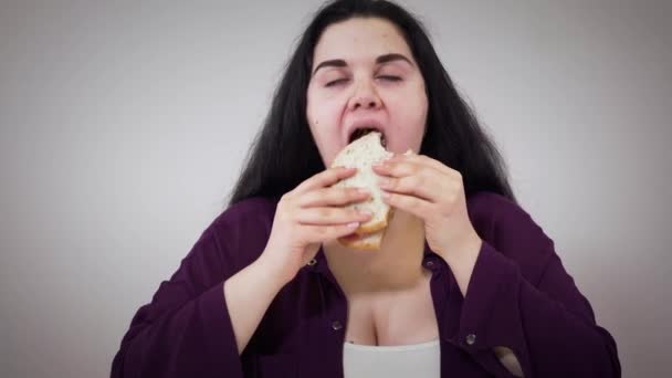 Detailní záběr tlusté bělošky žvýkající sendvič. Poslechněte mladou ženu, která jí nezdravé jídlo. Obezita, nezdravý životní styl, problém s nadváhou. — Stock video