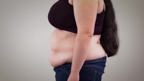 Egy közeli kép a felismerhetetlen fehér nőről, aki a hasát húzza és ellazít. Az elhízott nők testének oldalnézete. Elhízás, túlsúlyos probléma. — Stock videók