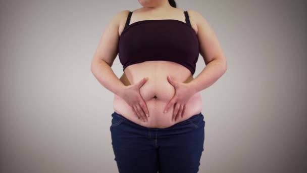 Onherkenbare blanke vrouw die vet schudt van de buik. Obese jonge vrouw die de buik aanraakt. Overgewicht, obesitas, ongezonde levensstijl. — Stockvideo