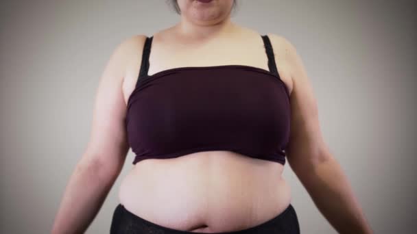 Wesoła, tłusta, biała dziewczyna mierząca klatkę piersiową za pomocą miernika taśmy. Otyła kobieta w bieliźnie ma problem z nadwagą. Niezdrowy tryb życia, otyłość. — Wideo stockowe