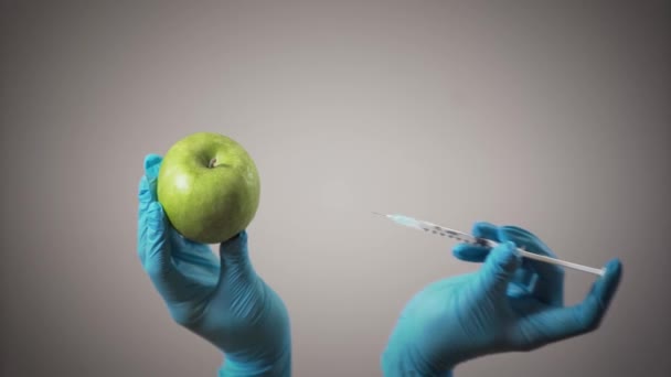 Frauenhände in medizinischen Handschuhen, die Injektionen in Apfel machen. gesunde und ungesunde Ernährung, gmo-Produkte, Chemie. — Stockvideo