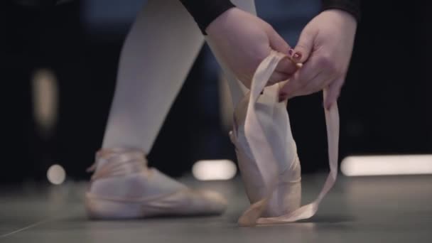 Slowmo of graceful unrecognizable Caucasian ballerina tying up pointes. Elegant female ballet dancer putting on ballet shoes. Grace, choreography, elegance, art. — 비디오