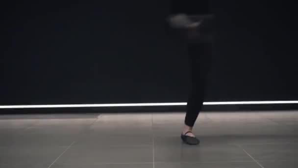 バレエダンサーの足から闇の中で回転する自信のある男の顔にカメラを上に移動します。ステージライトだけでプロのダンス。芸術、振付、優雅さ。スローモ. — ストック動画
