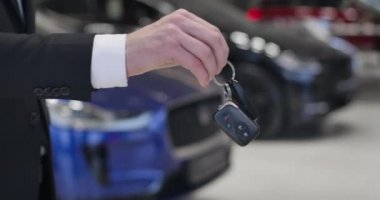 Beyaz bir erkeğin müşteriye araba anahtarı verip elini sıktığı yakın plan. Satıcı ve müvekkil otomobil alımıyla ilgili anlaşma yapıyorlar. Araba galerisi, otomobil endüstrisi. Sinema 4k Prores Merkezi.