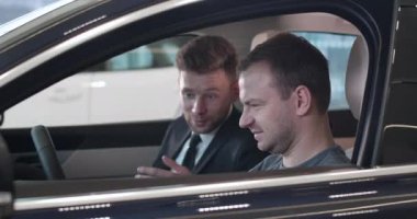 Kendine güvenen beyaz bir adamın araba anahtarlarını alıp motoru çalıştırmasının yan görüntüsü. Gülümseyen adam araba galerisinden yeni bir araç alıyor. Otomobil endüstrisi, başarı. Sinema 4k Prores Merkezi.