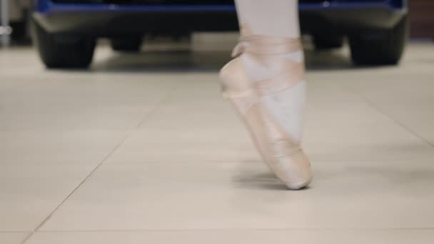 Vue de côté gros plan des pieds féminins en pointes en équilibre sur les pointe des pieds. Danseuse de ballet méconnaissable dansant dans un concessionnaire automobile. Industrie automobile, art, élégance . — Video