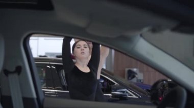 İki genç Kafkasyalı dansçı kameraya bakıyor. Kadın ve erkek araba galerisinde bale yapıyor. Otomobil salonundan çekim, ağır çekim. Performans, sanat, zarafet.