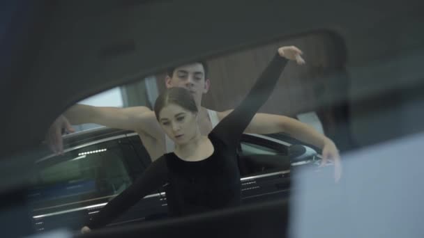 Dos bailarines de ballet caucásicos profesionales girando uno hacia el otro. Hombre y mujer confiados bailando en concesionarios de autos. Disparando por la ventana del coche. Elegancia, gracia, arte . — Vídeos de Stock