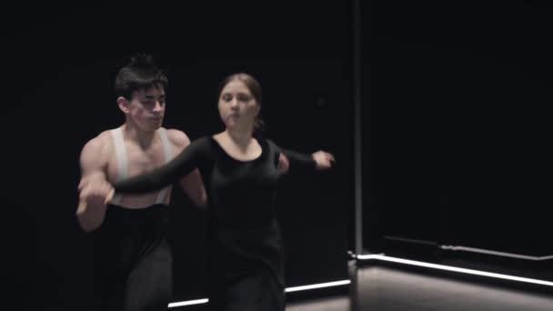 Zwei professionelle kaukasische Balletttänzer laufen vor die Kamera, die Frau springt auf, der Mann hält seine Partnerin. junges Paar tanzt in der Dunkelheit. Kunst, Performance, Eleganz, Stil. Zeitlupe. — Stockvideo