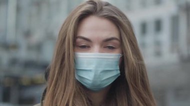 Şehir caddesinde koruyucu maske takmış yeşil gözlü güzel esmer kadının yakın plan portresi. Koronavirüs tehlikesi, koruma, sağlık hizmetleri.
