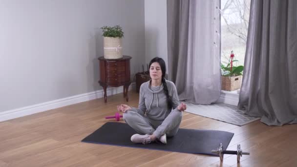 Bovenaanzicht lange shot van ontspannen blanke vrouw mediteren binnen. Mooie jonge vrouw die thuis yoga beoefent. Ontspanning, rust, levensstijl. — Stockvideo