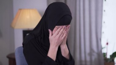 Evde ağlayan depresif Müslüman kadının portresi. Siyah tesettürlü yalnız, güzel bir kadın içeride oturuyor. Hayal kırıklığı, depresyon, üzüntü..