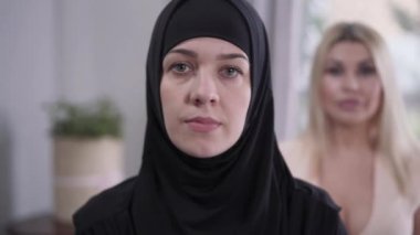 Odaklanma, tesettürlü mütevazı Müslüman bir kadından arkada duran Kafkasyalı sarışın bir kadına dönüşüyor. Modern toplumda kültürel çeşitliliğin dışa vurumu. Hoşgörü, çeşitlilik, yaşam tarzı.