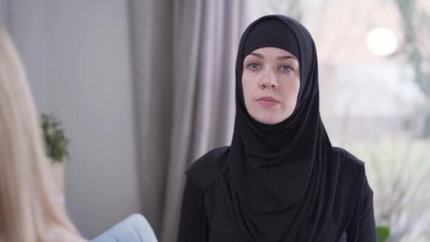 Focus verandert van bescheiden moslimvrouw in hijab naar jonge moderne blanke dame die naar de camera kijkt. Afbeelding van de diversiteit van de moderne samenleving. Tolerantie, levensstijl, schoonheid. — Stockvideo