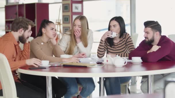 Gruppo di studenti caucasici adulti stanchi seduti a tavola a parlare. Giovani studenti universitari che imparano insieme. Educazione, studio, esaurimento, stress . — Video Stock