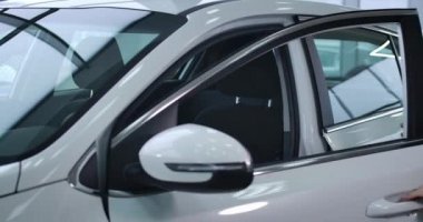 Caucasian businesswoman in elegant suit opening car door and sitting on drivers seat. Confident adult woman buying new white automobile in dealership. Cinema 4k ProRes HQ.