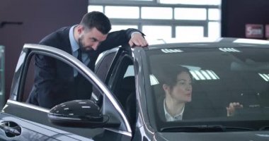 Arabada oturan başarılı bir iş kadınının portresi ve otomobilin yanında duran danışman bir satıcı. Bayilikten araç alan kendine güvenen beyaz bir kadın. Sinema 4k Prores Merkezi.