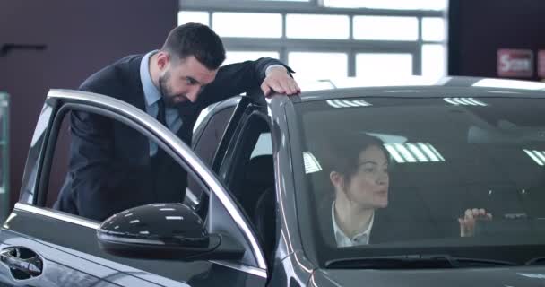 Portrait d'une femme d'affaires adulte prospère assise dans une voiture et concessionnaire consultant debout à côté de l'automobile. Femme caucasienne confiante achetant un véhicule chez un concessionnaire. Siège social Cinema 4k ProRes . — Video