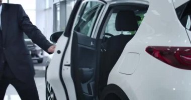 Profesyonel şoför, alışveriş çantalı başarılı sarışın iş kadını için kapıyı açıyor. Başarı, işgal, otomobil. Sinema 4k Prores Merkezi.