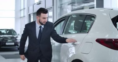 Esmer ve meşgul bir iş kadını için araba kapısını açan Kafkasyalı ciddi bir sürücü. Zengin ve başarılı bir kadın için çalışan profesyonel bir şoför. Sinema 4k Prores Merkezi.