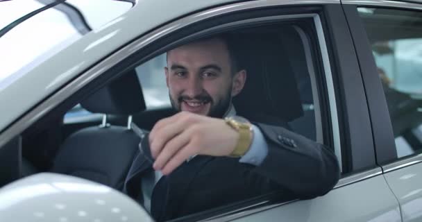 Successful handsome Caucasian businessman showing car keys at camera and smiling. Happy automobile owner posing in dealership in new vehicle. Auto industry, success. Cinema 4k ProRes HQ. — 비디오