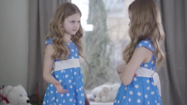 Side view of pretty brunette Caucasian twins arguing indoors. Two identical sisters in beautiful dresses quarreling at home. Conflict, communication problems, family. — Stock Video