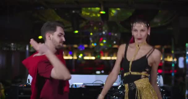 Cheerful young Caucasian man and woman dancing in night club next to DJ controller. Handsome male DJ and seductive female go go dancer entertaining in disco. Cinema 4k proRes HQ. — Stock Video