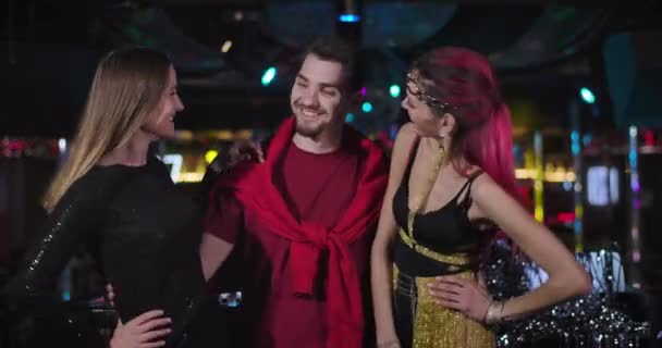 Retrato de un joven apuesto DJ caucásico posando con dos bailarines de go go en un club nocturno. Sonriendo personas positivas de pie en la discoteca y mirando a la cámara. Sede del cine 4k ProRes . — Vídeos de Stock