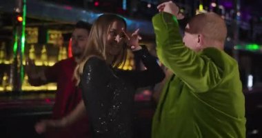 Funny old Caucasian man in green jacket flirting with young beautiful woman in night club. Elderly guy dancing with cute lady in black dress in disco. Cinema 4k ProRes HQ.