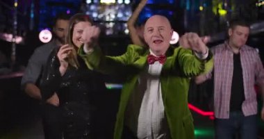 Portrait of cheerful senior Caucasian man and young pretty woman dancing in night club and looking at camera. Joyful old guy and elegant lady in black dress having fun in disco. Cinema 4k ProRes HQ.